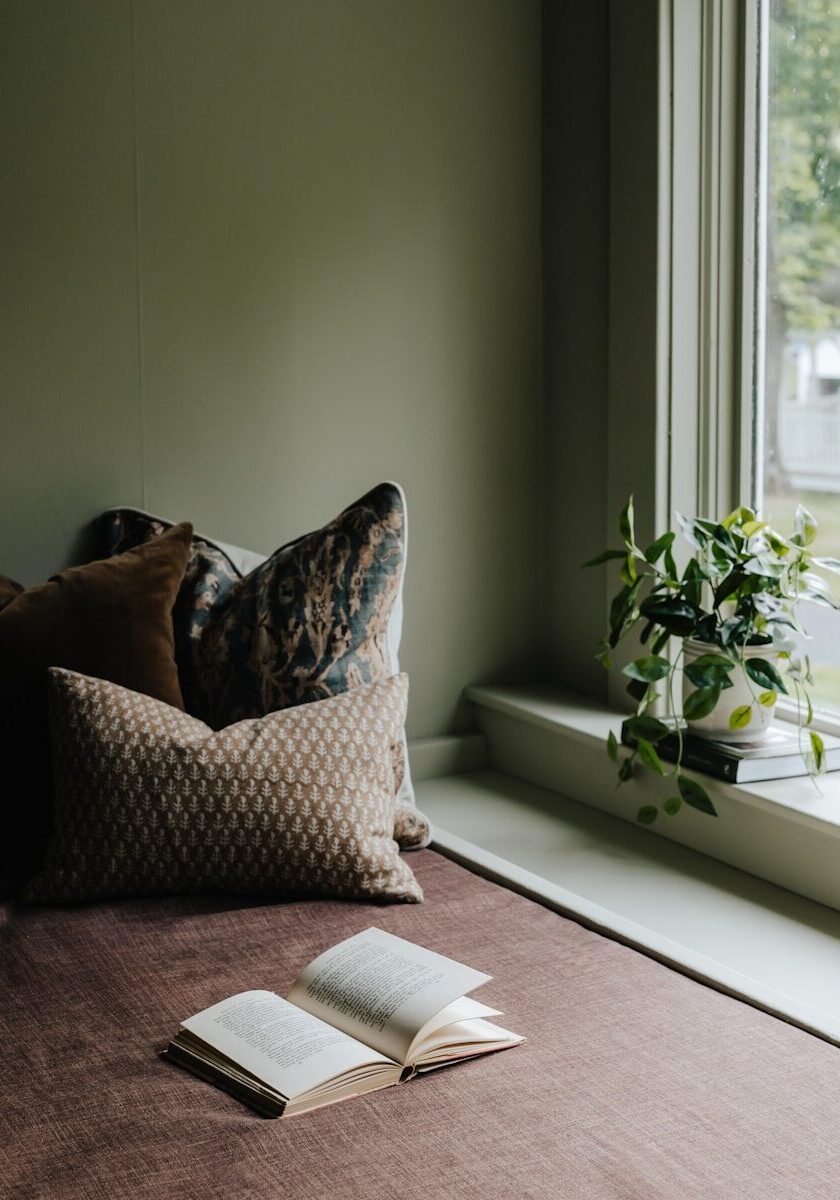 A bed with a book on top of it next to a window